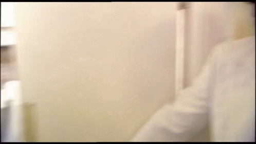 A Blurry Picture Of A Man 'S Face Behind A White Wall . GIF