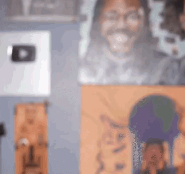 A Blurry Picture Of A Man 'S Face Is Hanging On A Wall Next To A Painting Of A Cat . GIF