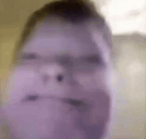A Blurry Picture Of A Man 'S Face With A Purple Background . GIF