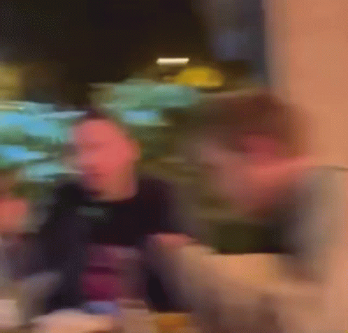 A Blurry Picture Of A Man Sitting At A Table In A Restaurant Eating Food . GIF