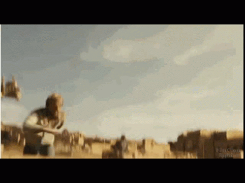 A Blurry Picture Of A Man Standing In A Field With Buildings In The Background . GIF