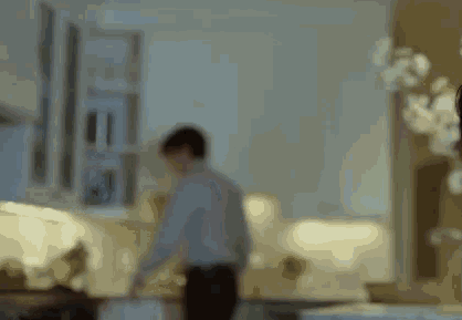 A Blurry Picture Of A Man Standing In A Living Room With A Couch . GIF
