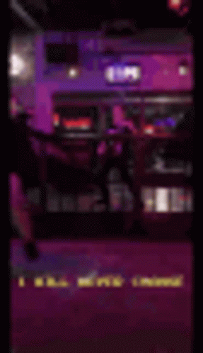 a blurry picture of a man standing on a stage in a dark room with purple lights .