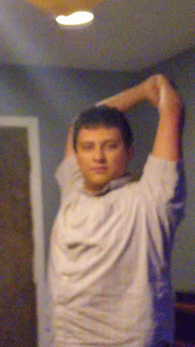 A Blurry Picture Of A Man Stretching His Arms In A Room GIF