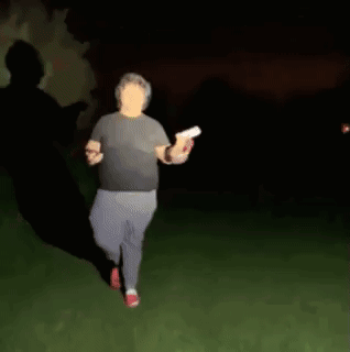 A Blurry Picture Of A Man Walking In The Dark Holding A Frisbee . GIF
