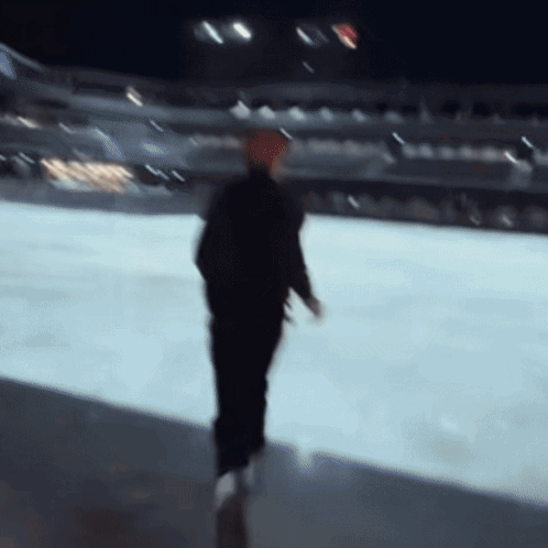 A Blurry Picture Of A Man Walking On A Ice Rink GIF