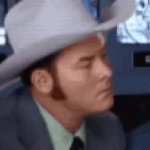 A Blurry Picture Of A Man Wearing A Cowboy Hat And A Suit GIF