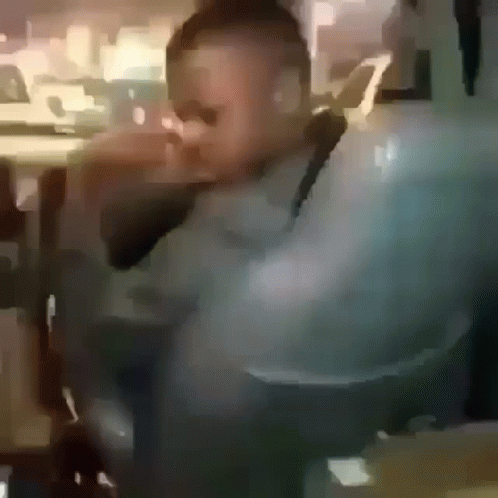 A Blurry Picture Of A Man Wearing Sunglasses Sitting In A Chair . GIF