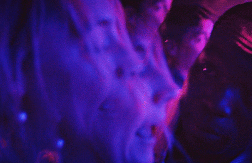 A Blurry Picture Of A Person 'S Back With Purple And Blue Lights Behind Them GIF