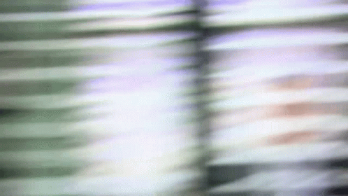 A Blurry Picture Of A Person 'S Face Behind Blinds GIF