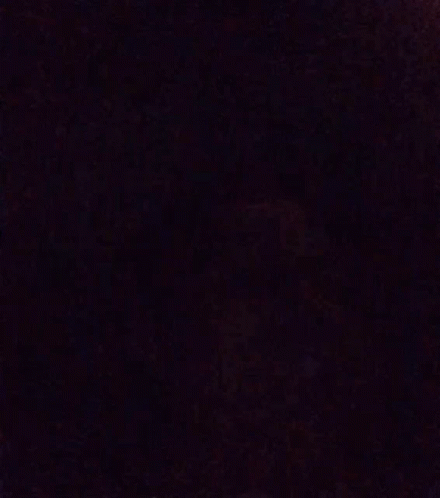 A Blurry Picture Of A Person 'S Face In A Dark Room With A Purple Background . GIF