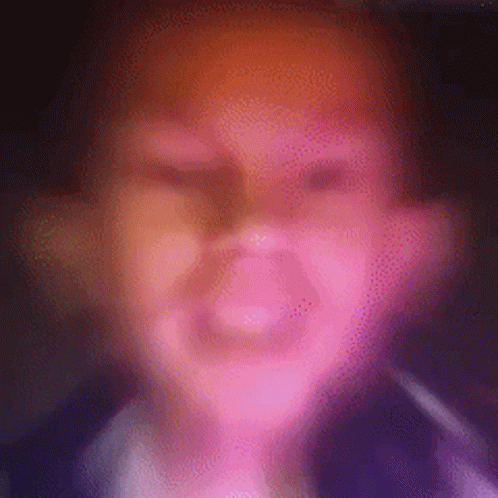 A Blurry Picture Of A Person 'S Face With A Pink And Orange Background . GIF