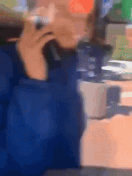 A Blurry Picture Of A Person Sitting At A Table Talking On A Cell Phone GIF