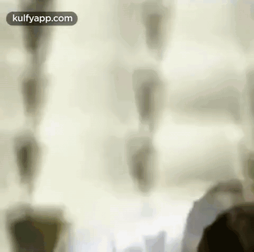 A Blurry Picture Of A Person Standing In Front Of A Window With A White Curtain . GIF