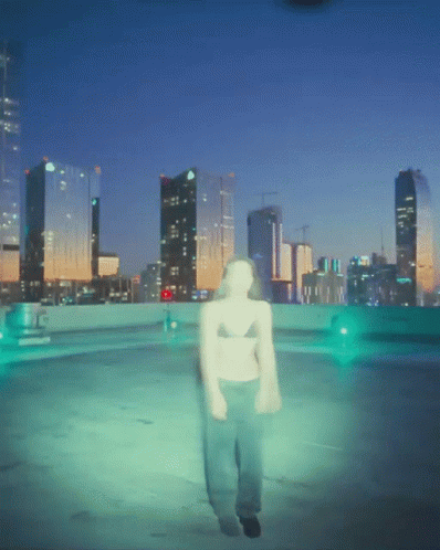 A Blurry Picture Of A Person Walking In Front Of A City Skyline At Night GIF