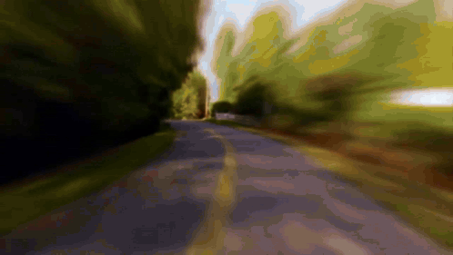 A Blurry Picture Of A Road Going Through A Forest GIF