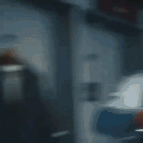 A Blurry Picture Of A Room With A Red Chair And A White Wall GIF