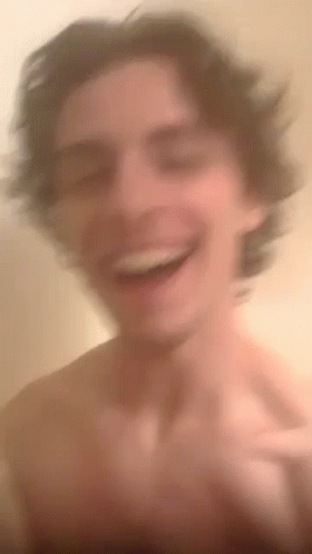 A Blurry Picture Of A Shirtless Man Laughing And Smiling . GIF