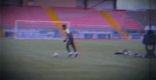 a blurry picture of a soccer field with a yellow pole