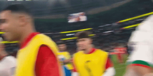 A Blurry Picture Of A Soccer Game With Players In Yellow Vests GIF