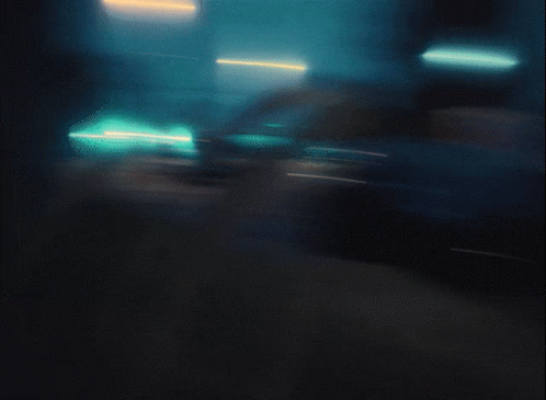 A Blurry Picture Of A Street At Night With Cars Parked On The Side Of The Road GIF