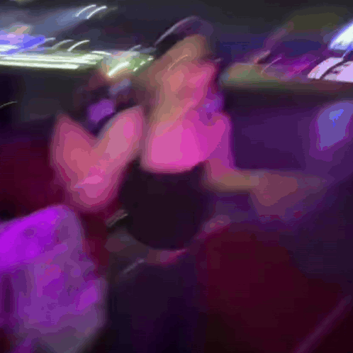 A Blurry Picture Of A Woman Dancing In A Club With A Chair In The Foreground GIF
