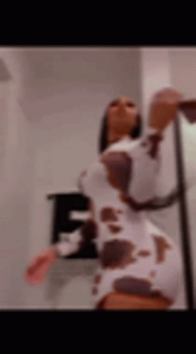 A Blurry Picture Of A Woman In A Cow Print Dress Dancing . GIF