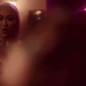 A Blurry Picture Of A Woman In A Dark Room With Purple Lights Behind Her GIF