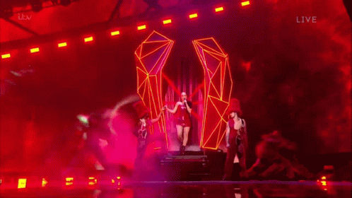 A Blurry Picture Of A Woman In A Red Dress On A Stage With Itv Live In The Lower Right Corner GIF