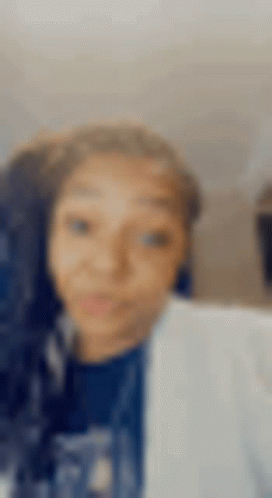 A Blurry Picture Of A Woman 'S Face With A Blue Shirt On . GIF