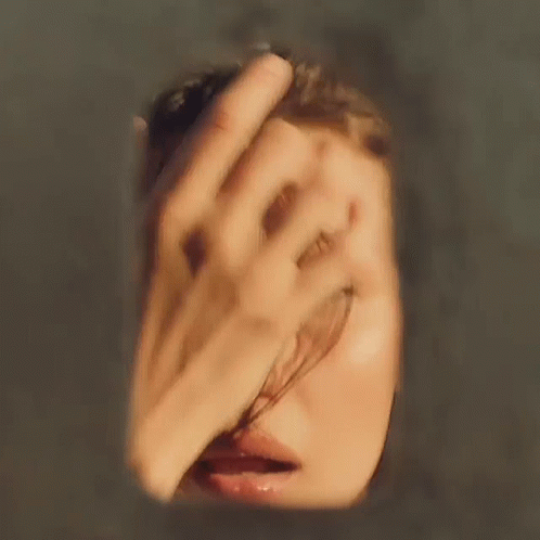 A Blurry Picture Of A Woman 'S Face With A Hand Covering Her Face GIF