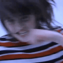 A Blurry Picture Of A Woman Wearing A Striped Shirt With Her Hair Blowing In The Wind . GIF