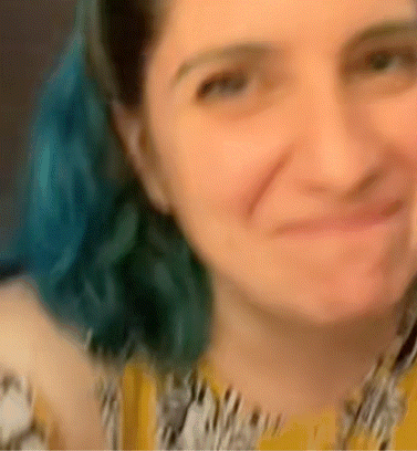 A Blurry Picture Of A Woman With Blue Hair And A Yellow Shirt GIF