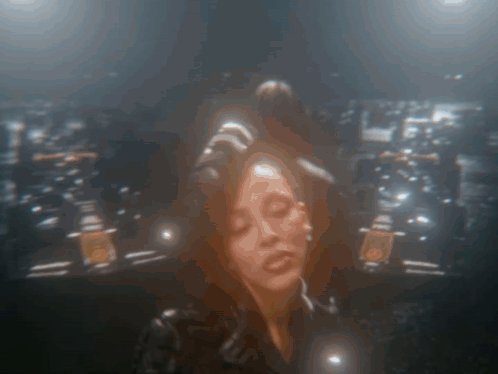 A Blurry Picture Of A Woman With Her Eyes Closed In A Dark Room GIF
