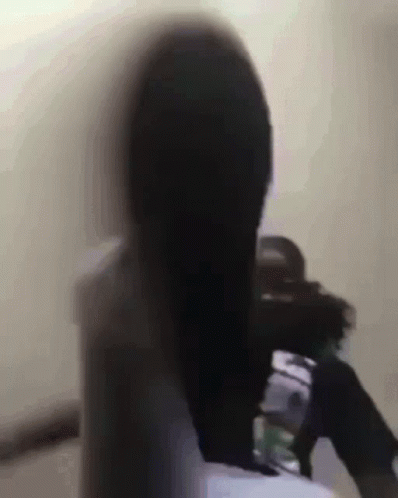 A Blurry Picture Of A Woman With Long Black Hair Sitting In A Chair GIF
