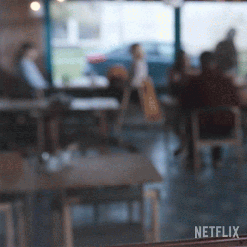 A Blurry Picture Of People Sitting At Tables In A Restaurant With Netflix Written On The Bottom Right GIF