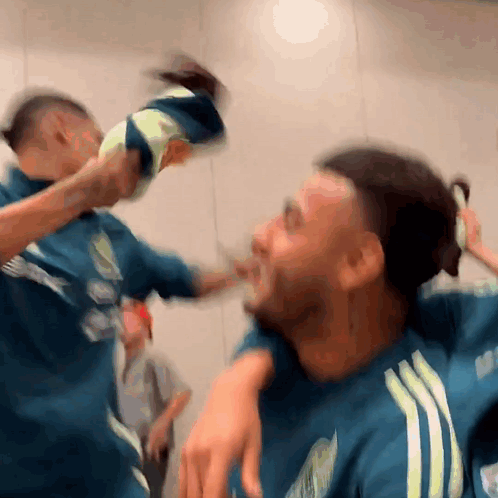 A Blurry Picture Of Two Men Fighting With One Wearing A Blue Adidas Shirt GIF