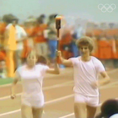 a blurry picture of two people running with a torch in their hands