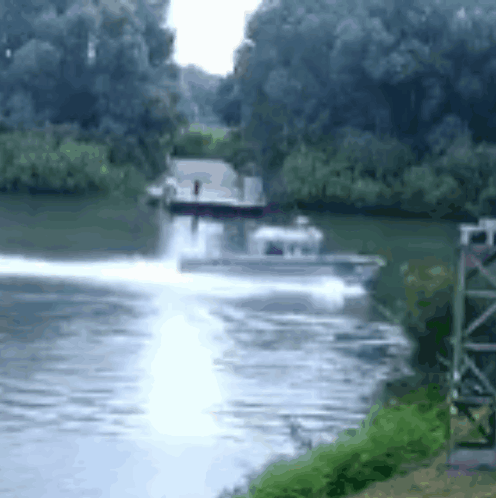 A Boat Is Speeding Down A River With Trees On The Shore GIF