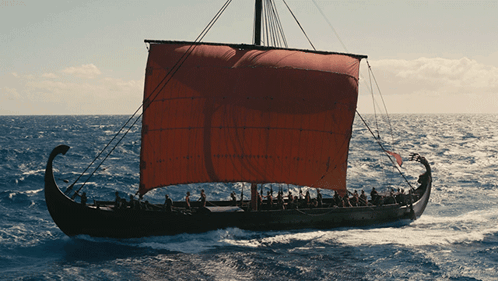 A Boat With A Red Sail Is Floating On The Water GIF