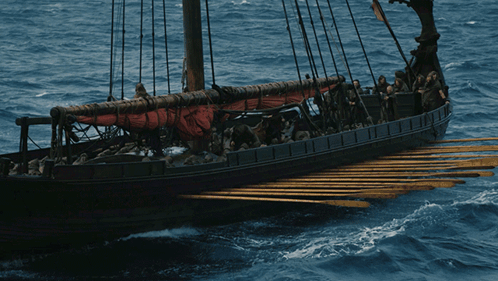 A Boat With A Red Sail Is Floating On The Water GIF