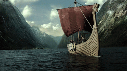 A Boat With A Red Sail Is In The Middle Of A River GIF