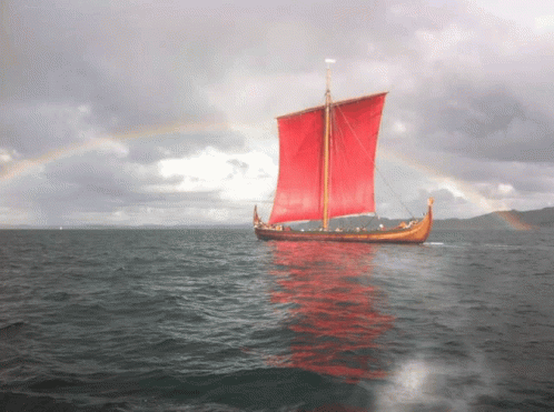 A Boat With Red Sails Is In The Ocean GIF