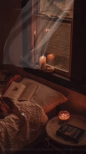 A Book On A Table Next To A Window With Candles And A Pumpkin GIF