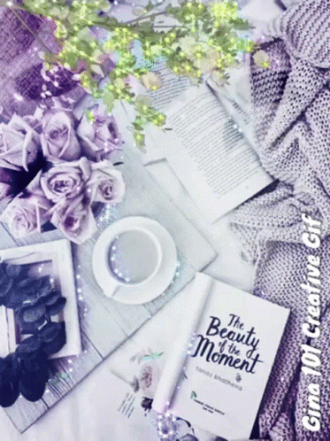 A Book Titled " The Beauty Of The Moment " Sits On A Table GIF
