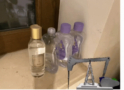 A Bottle Of Baby Oil Sits Next To A Bottle Of Perfume GIF