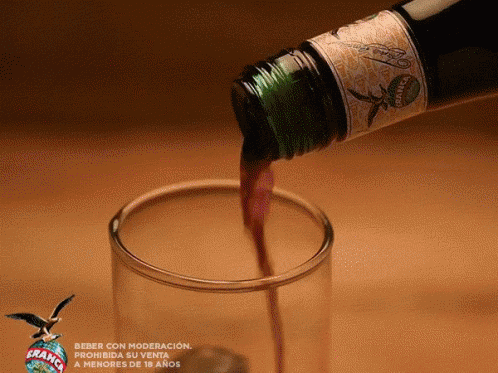 A Bottle Of Brandy Is Pouring Into A Glass GIF
