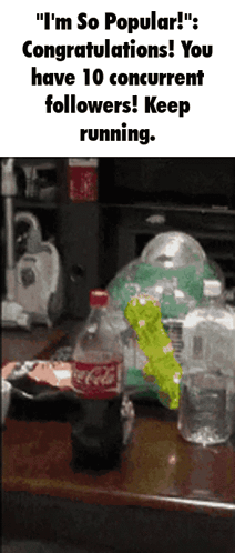 A Bottle Of Coca Cola Sits On A Table Next To A Pile Of Other Bottles GIF