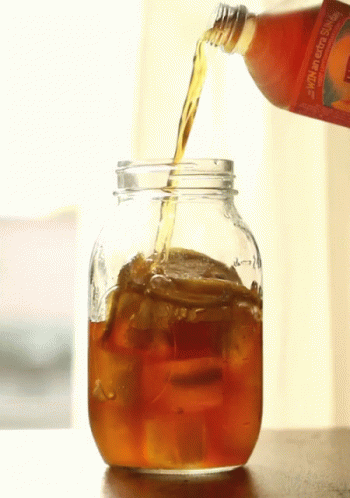 A Bottle Of Orange Juice Is Poured Into A Glass Jar GIF