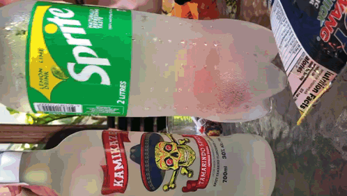 A Bottle Of Sprite Sits Next To A Bottle Of Kamikaze Tamarind Sprit GIF